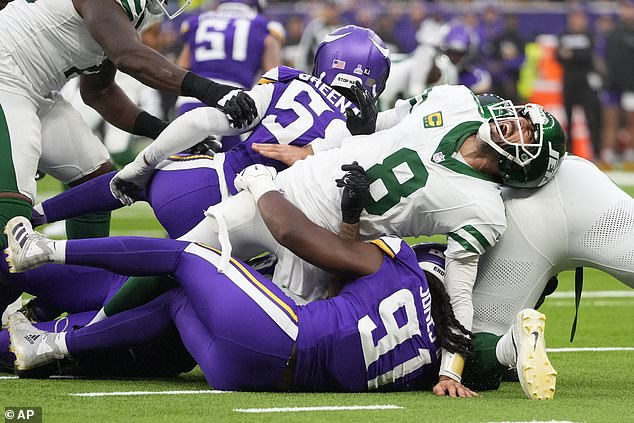 New York Jets quarterback Aaron Rodgers (8), right, reacts as he is tackled during the second half of an NFL football game against the Minnesota Vikings