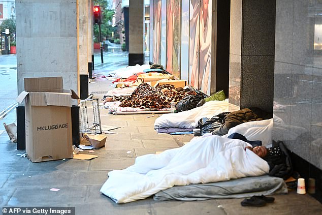 Pictured: Rough sleepers lie in their makeshift beds outside closed shops at dawn on London's Oxford Street on August 2, 2023