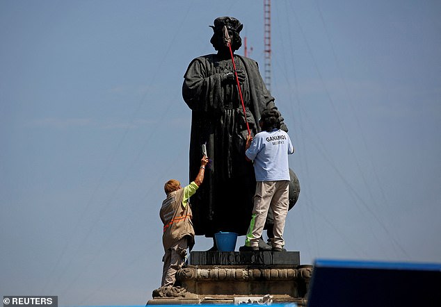 Workers clean the statue of Italian explorer Cristobal Colon, also known as Christopher Columbus, surrounded by metal fencing during Columbus Day, or Day of the Race (Dia de la Raza), commemorating the time Colon came to America , in Mexico City. Mexico October 12, 2020