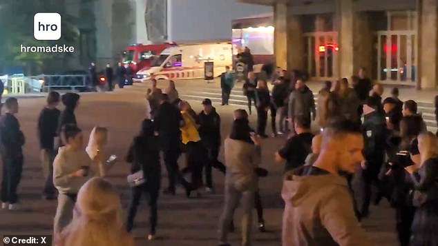 A man in yellow is seen being dragged away by police officers (pictured)