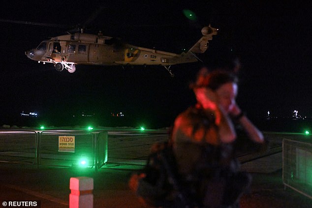 An Israeli soldier stands by as a military helicopter takes off after dropping off patients injured in a drone strike