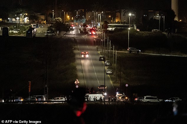 Israeli security forces and first responders gather at the scene of a drone strike as an ambulance drives by