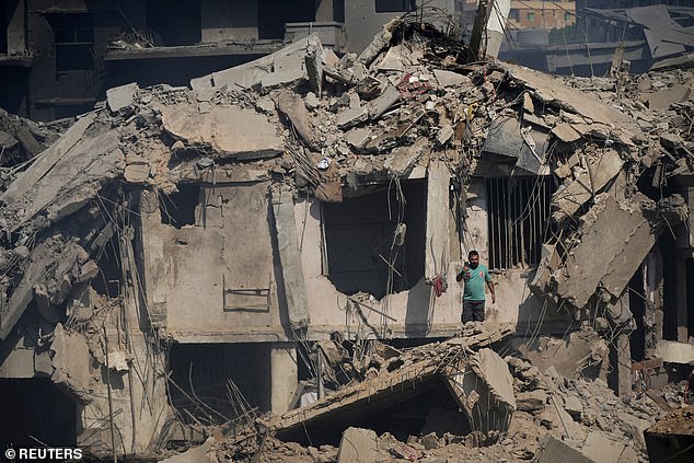 A civil defense member stands amid damage in the aftermath of what security sources say was an Israeli attack on a market in southern Lebanon