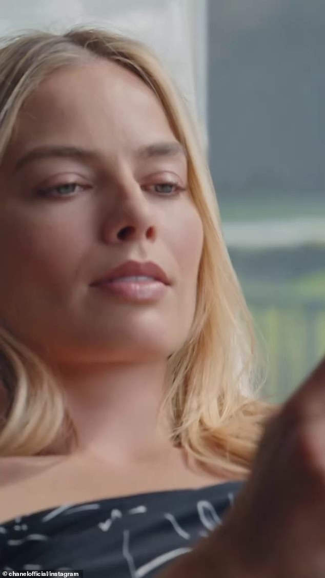 The commercial, directed by Luca Guadagnino, opens with Margot looking as glamorous as ever in a black dress as she sits on a window seat and checks her phone.