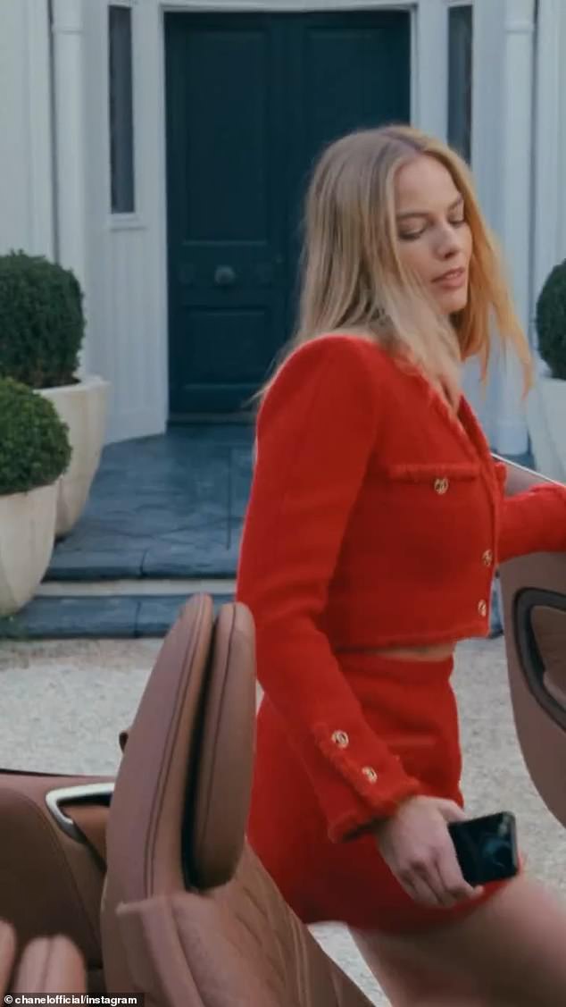 The Barbie actress then dons an elegant red two-piece suit and applies Chanel No5 for her date as she climbs into a luxury roofless car to visit her loved one.