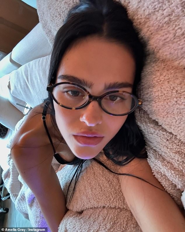 She was also pictured lying in bed wearing stylish glasses