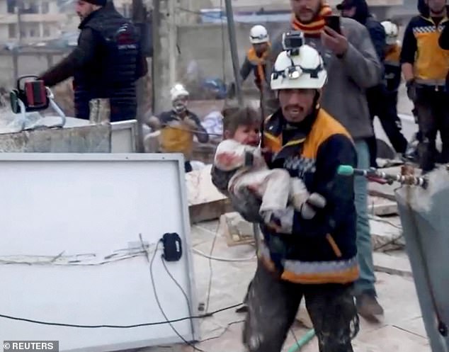 Pictured: A rescue worker carried an injured child from the rubble of a collapsed building in rebel-held Syria, after a deadly earthquake struck Turkey and Syria in 2023