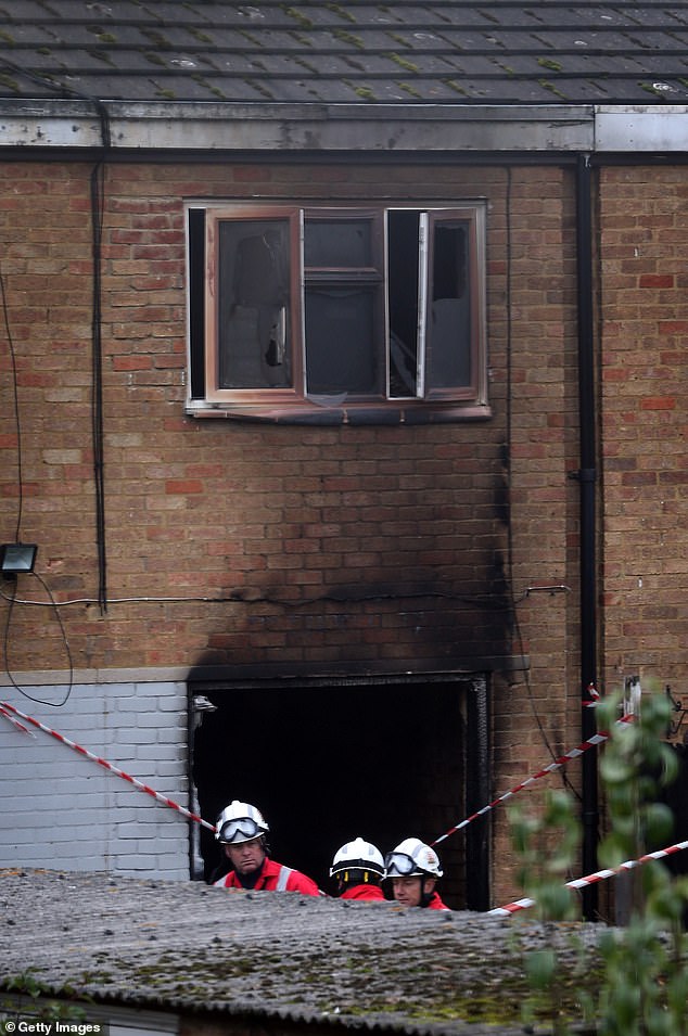 Firefighters inspect the rear of a fire that killed Dr. Shakoor's wife and children on October 15, 2012