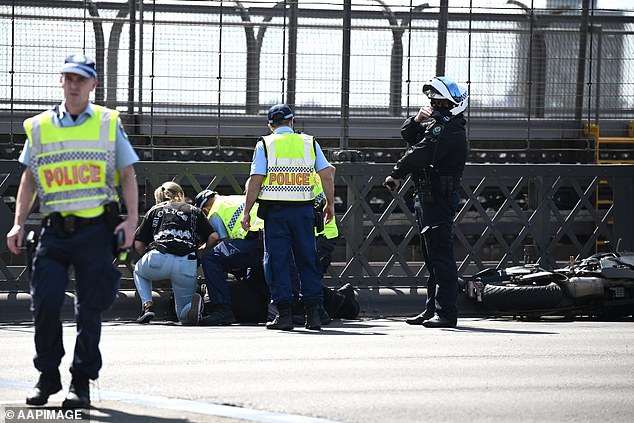 Police later arrested a motorcyclist who allegedly broke the roadblock and drove through the accident scene (pictured)