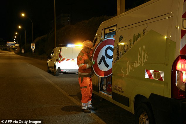 A construction worker loads a 70 km/h traffic sign into a truck after installing a 50 km/h speed limit sign on the Paris ring road, the boulevard peripherique, at the Porte d'Ivry in Paris