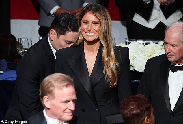 Melania stands with a dazzling smile