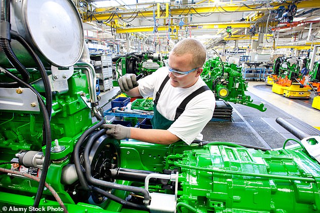 John Deere employees work on agricultural machinery. The company is laying off employees