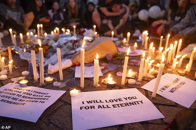 Candles are placed on the sidewalk as fans of former One Direction singer Liam Payne gather to honor him