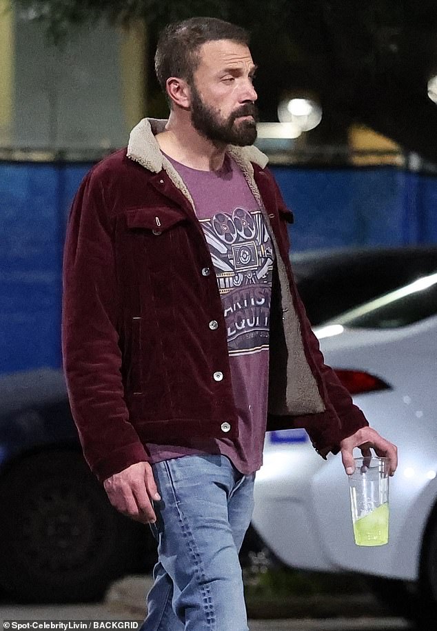 Ben kept it casual and wore light blue jeans, a red printed shirt and a dark red jacket while holding a drink