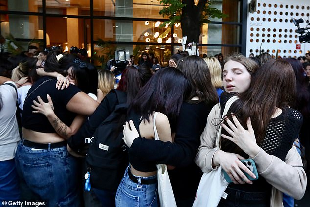 Mourning fans of Liam Payne hug each other after Geoff Payne, Liam's father, visited the memorial