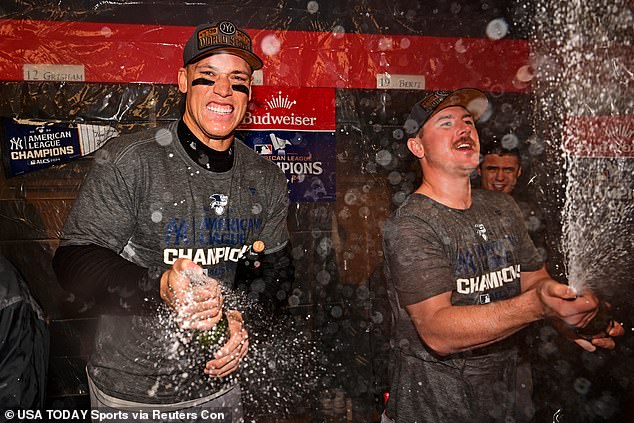 New York captain Aaron Judge (left) sprays champagne after beating the Cleveland Guardians