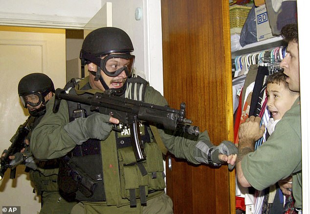 Pictured: Elian Gonzalez, 6, is held in a closet by Donato Dalrymple, right, as government officials search for the boy at his relative's home in Miami on April 22, 2000