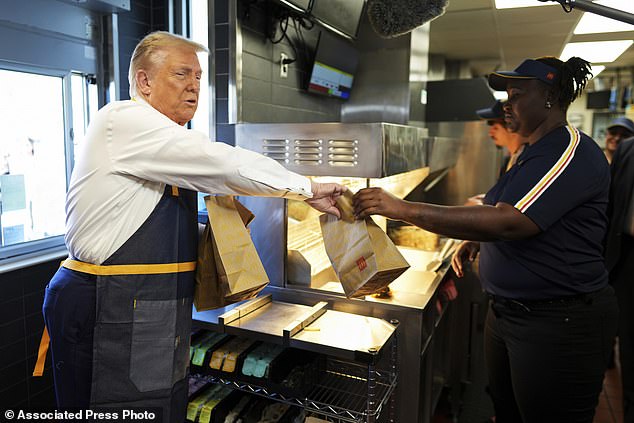 An employee hands a warrant to Republican presidential candidate, former President Donald Trump, during a visit to McDonald's in Feasterville-Trevose, Pennsylvania