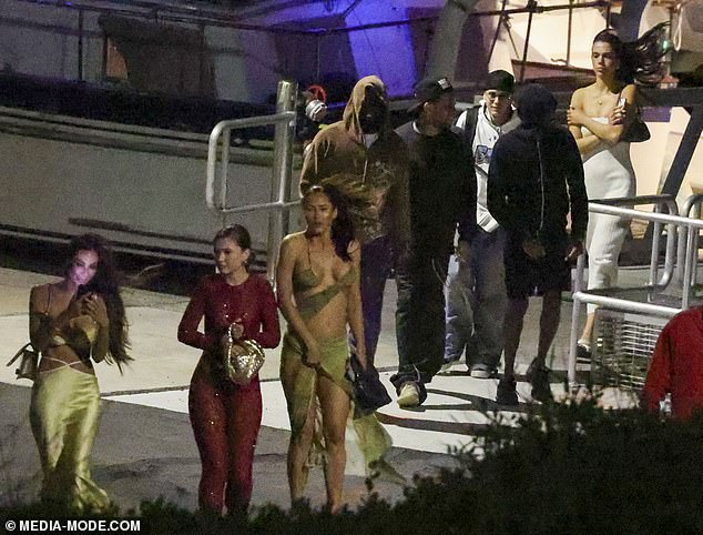 Travis' female guests that night opted for figure-hugging outfits that showed off their striking curves. One guest could barely contain her copious assets in a green ensemble precariously held together by strands of fabric and a prayer (pictured right)