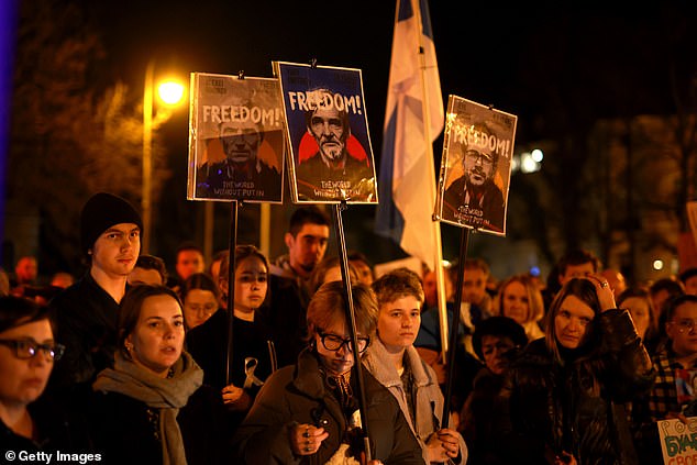 People hold signs during a vigil for Alexiei Navalny in front of the Russian Consulate General on February 16, 2024 in Munich, Germany