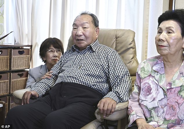 Iwao Hakamada, center, sits next to his sister, right, as Tsuda came to his house to apologize