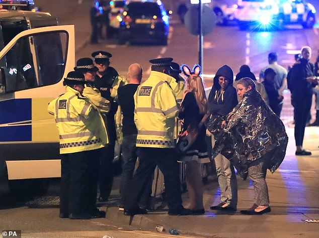 In the photo, police officers speak to people who attended the Ariana Grande concert at Manchester Arena