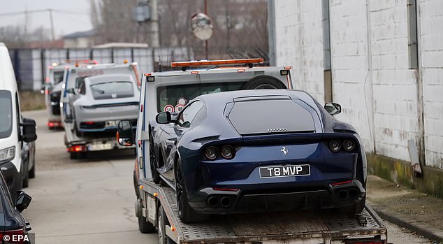 A Ferrari sports car owned by Andrew Tate is taken by Romanian law enforcement officers on a transport platform from his property in January 2023