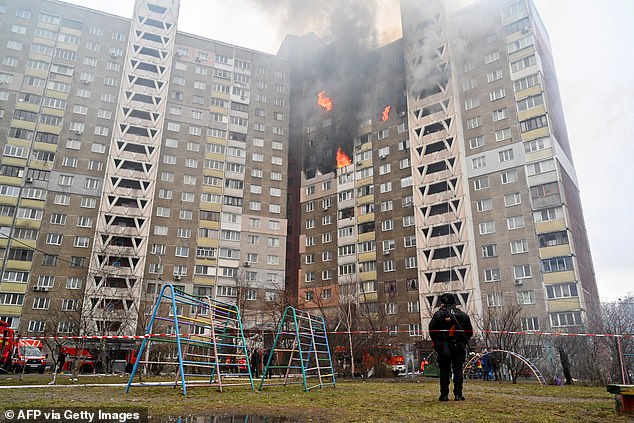 A law enforcement officer stands next to a residential building damaged as a result of a rocket attack in Kiev on February 7, 2024