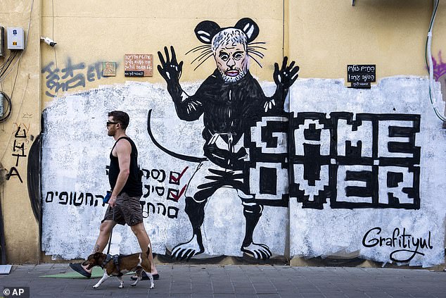 People pass by a newly painted graffiti depicting Hamas leader Yahya Sinwar, days after he was killed by Israeli forces in Gaza, in Tel Aviv, Israel, on Sunday, October 20, 2024