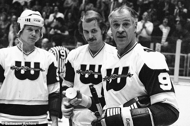 A little fatherly advice as hockey great Gordie Howe accepts a golden puck from his sons and teammates Mark and Marty Howe (c) in recognition of his 1,000th goal