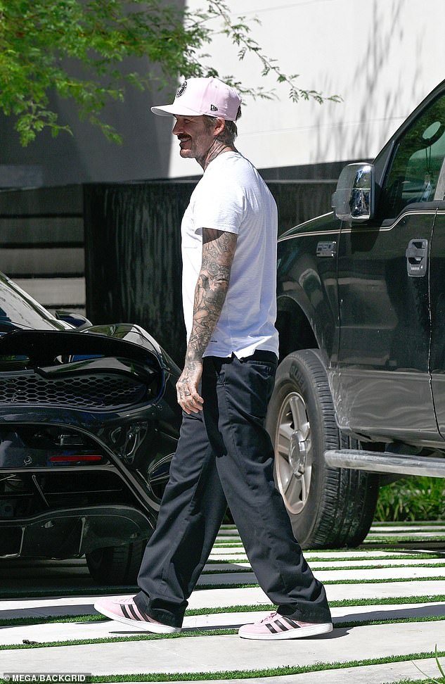 Beckham is photographed smiling for the cameras after entering the gated compound