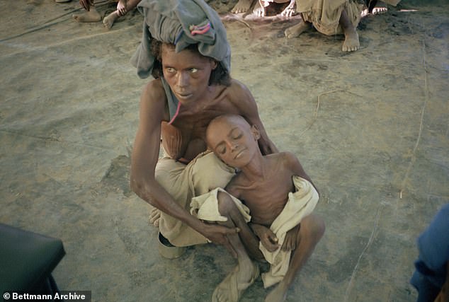 At the Mile Feeding Station, in the midst of the Ethiopian famine, a mother holds her child as she waits for food, March 12, 1984