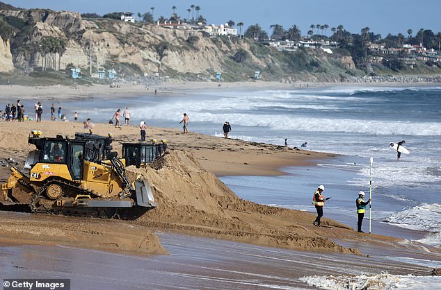 Workers measure the sand height along fresh sand during a sand replenishment project