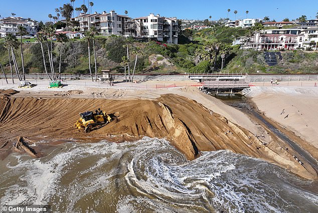 An excavator moves newly delivered sand to a public beach in San Clemente as part of a sand replenishment project