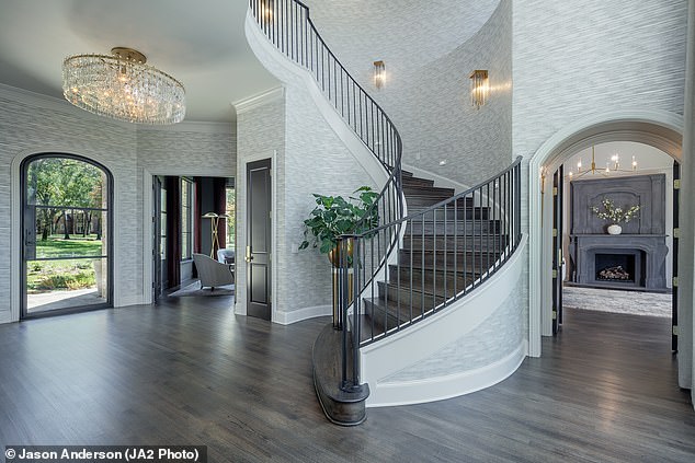 At the main entrance there is a spiral staircase bordered by a railing, while an ornate chandelier hangs nearby