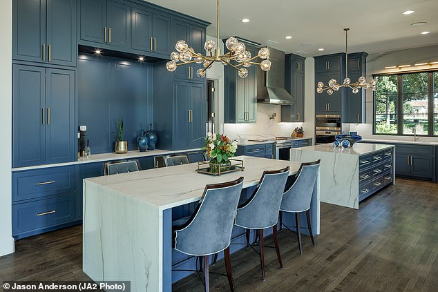 The kitchen area contains two islands, blue-colored cabinets and two modern lamps hanging from the ceiling