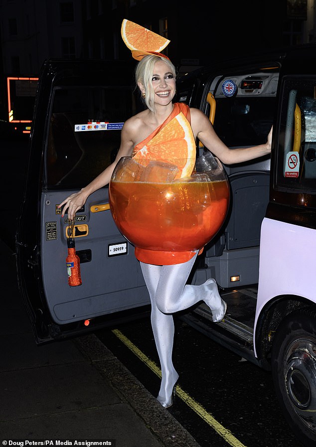 The pop star was dressed in a bright orange one-shoulder mini dress, which she paired with silver metallic tights and boots and orange accessories.