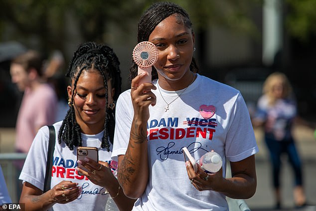 A Harris supporter holds up a fan as she waits for the vice president's rally in Houston