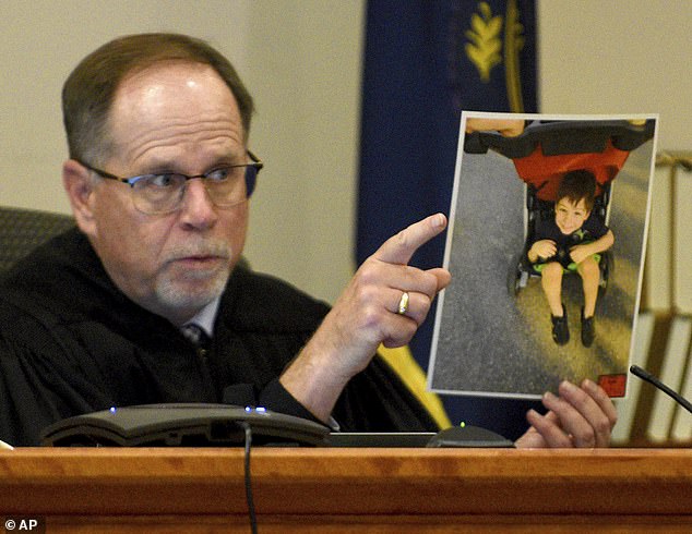 Supreme Court Justice Charles Temple holds a photo of Elijah Lewis as he explains his sentence during the hearing for Danielle Dauphinais at Hillsborough County Superior Court South in Nashua, New Hampshire on Friday