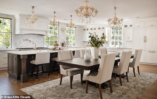 The kitchen has a long island with a marble countertop and dark wood cabinets. It matches the rest of the room with its hardwood floors and bright cabinetry