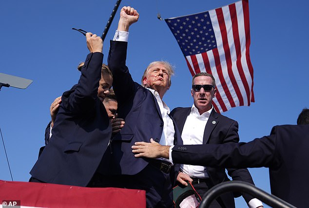 Trump is seen here gesturing to a gathering of his supporters after he was shot in the ear at an event in Butler, Pennsylvania, in July