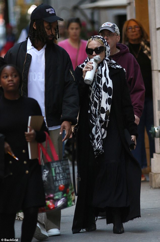 She wore a long black trench coat and dress and hid her bleached locks with a patterned scarf. The signer paired her cozy look with oversized designer sunglasses