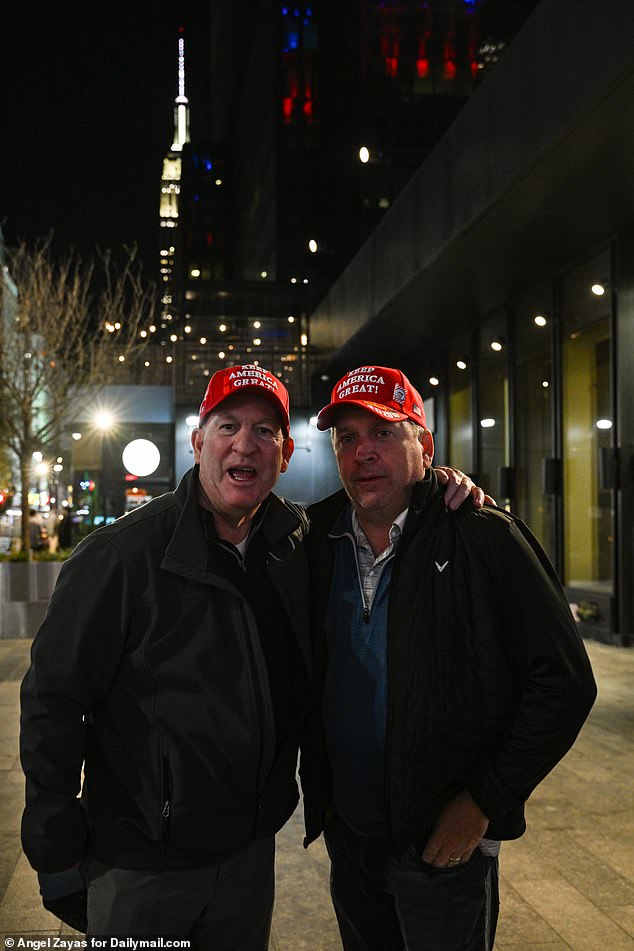 Trump supporters pose for a photo wearing their red MAGA baseball hats outside the arena