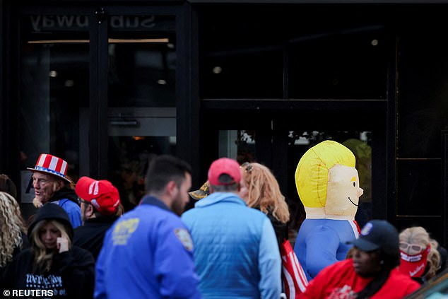 People dressed in patriotic colors are seen outside the arena, along with an inflatable Trump figure