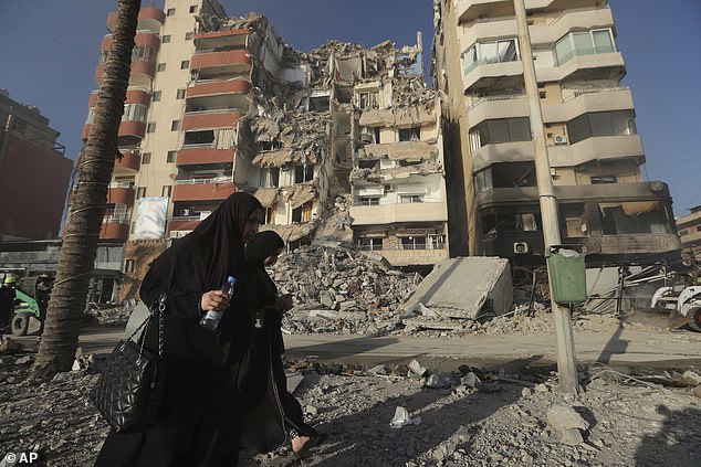 Lebanese women pass a destroyed building hit by an Israeli airstrike in Tyre, Lebanon, Monday, October 28, 2024