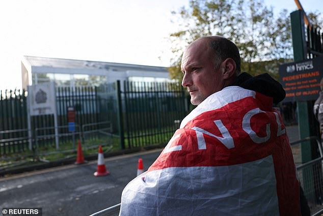 A man with an English flag watches as Robinson supporters gather outside Woolwich Crown Court