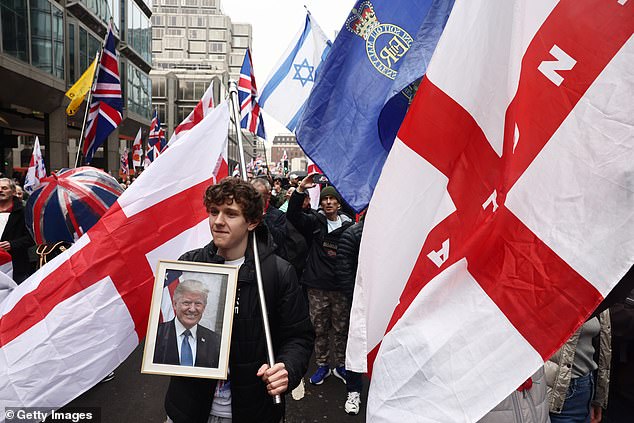 A young man holds a photo of Donald Trump as he marches through London as part of the crowd