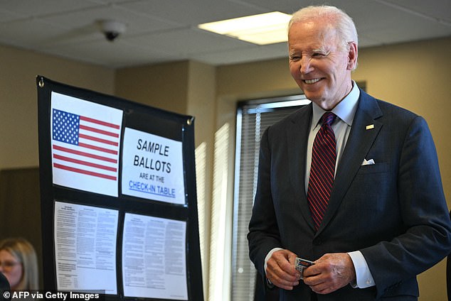 Biden, 81, smiles with his driver's license in his hand as he waits to vote with other Delawareans