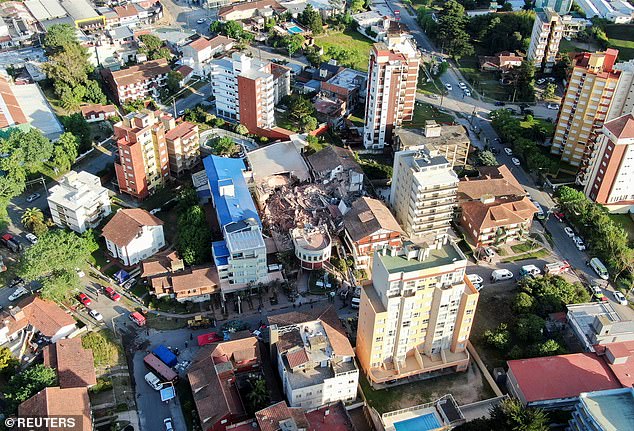 Dramatic aerial photos show a pile of rubble where the building once stood, among other high-rise blocks