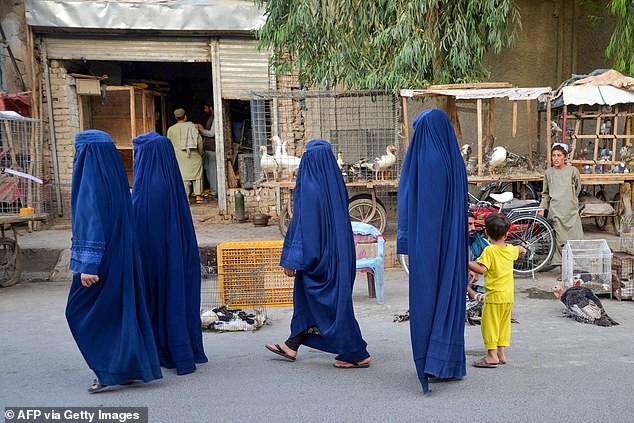 Afghan women wearing burqas walk down a street in Kandahar on September 3, 2024